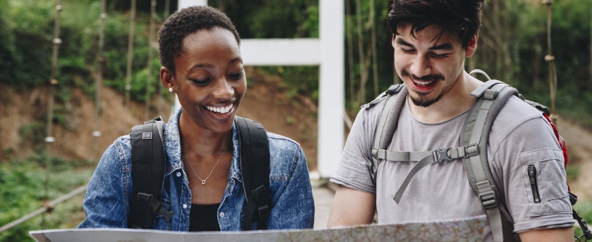 Tourists looking at map in jungle | Compare travel insurance